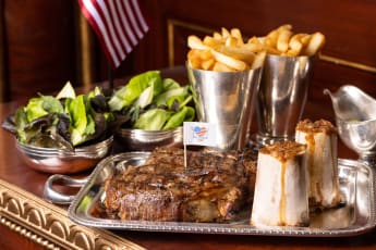 Grilled bone-in Rib of beef (900g) Served with Roasted bone Marrow, Pickled Shallots, French Fries, Mixed Leaves and Herbs; with Choice of Bearnaise / Peppercorn/ or Charcuterie Sauce