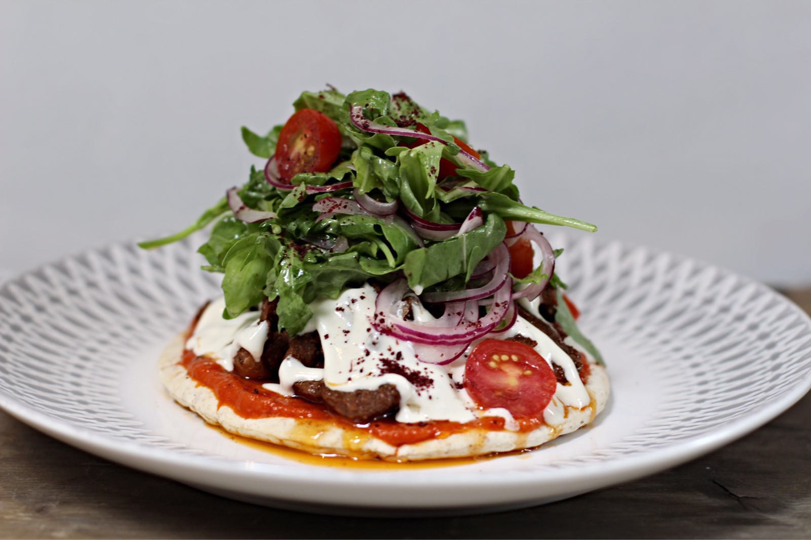 Open duck shawarma with harissa, tahini, sumac, rocket salad, Arabic bread